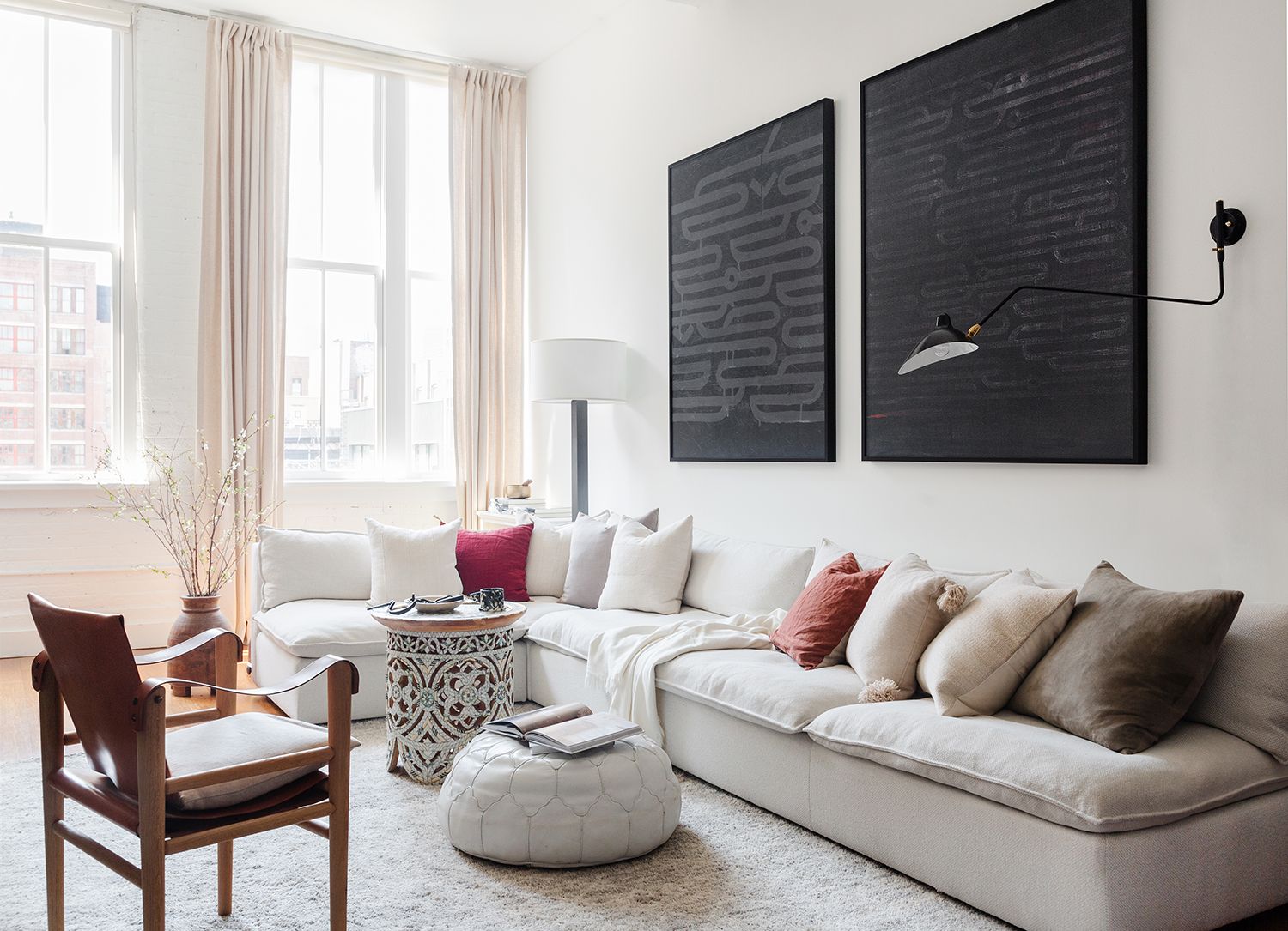 Contemporary living room with cream round storage ottoman anchoring neutral palette and natural light
