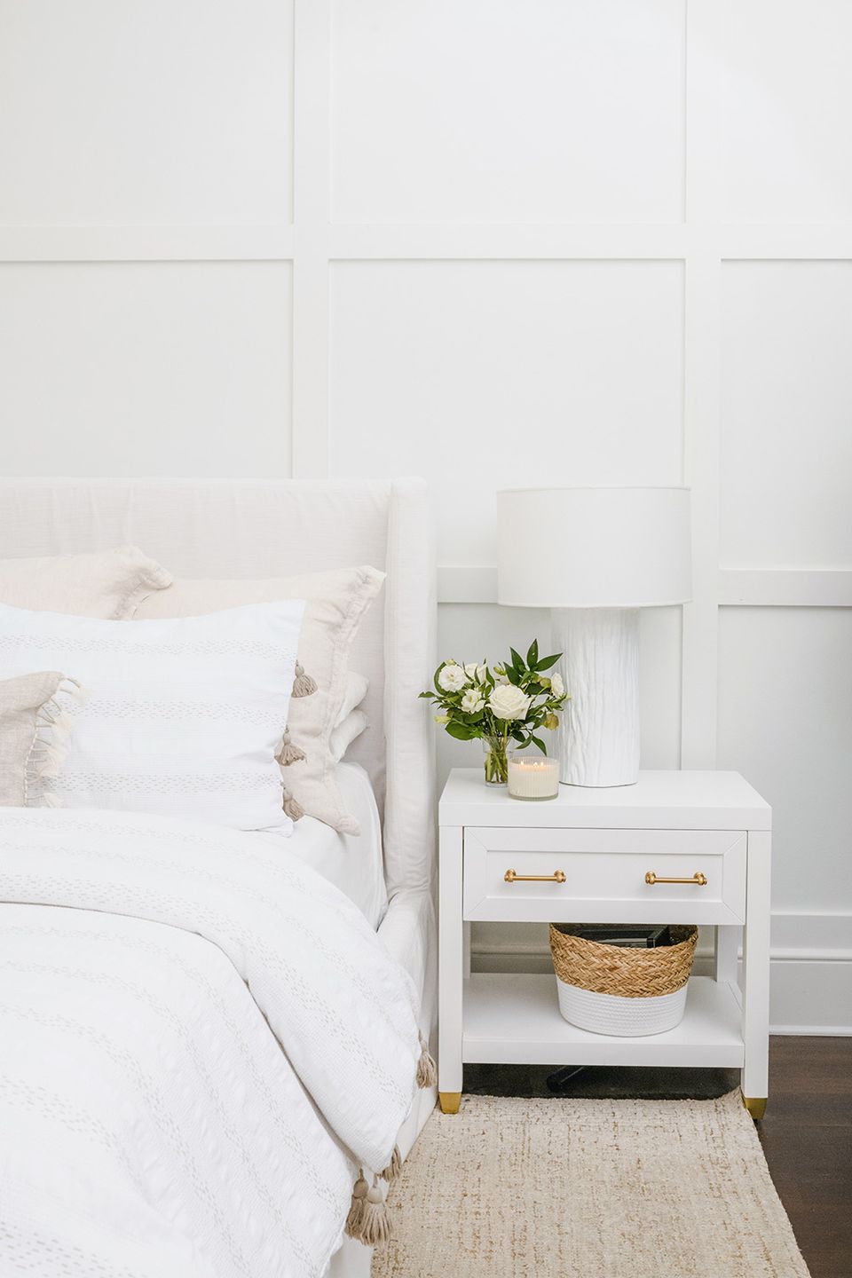 Clean white bedroom with raised panel accent wall, soft neutral tones, and airy elegance