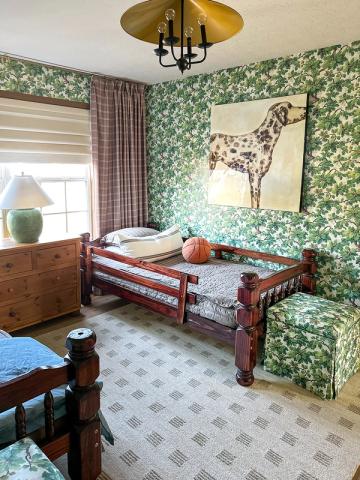 Eclectic maximalist bedroom mixing green botanical wallpaper, plaid curtains, and wood furniture