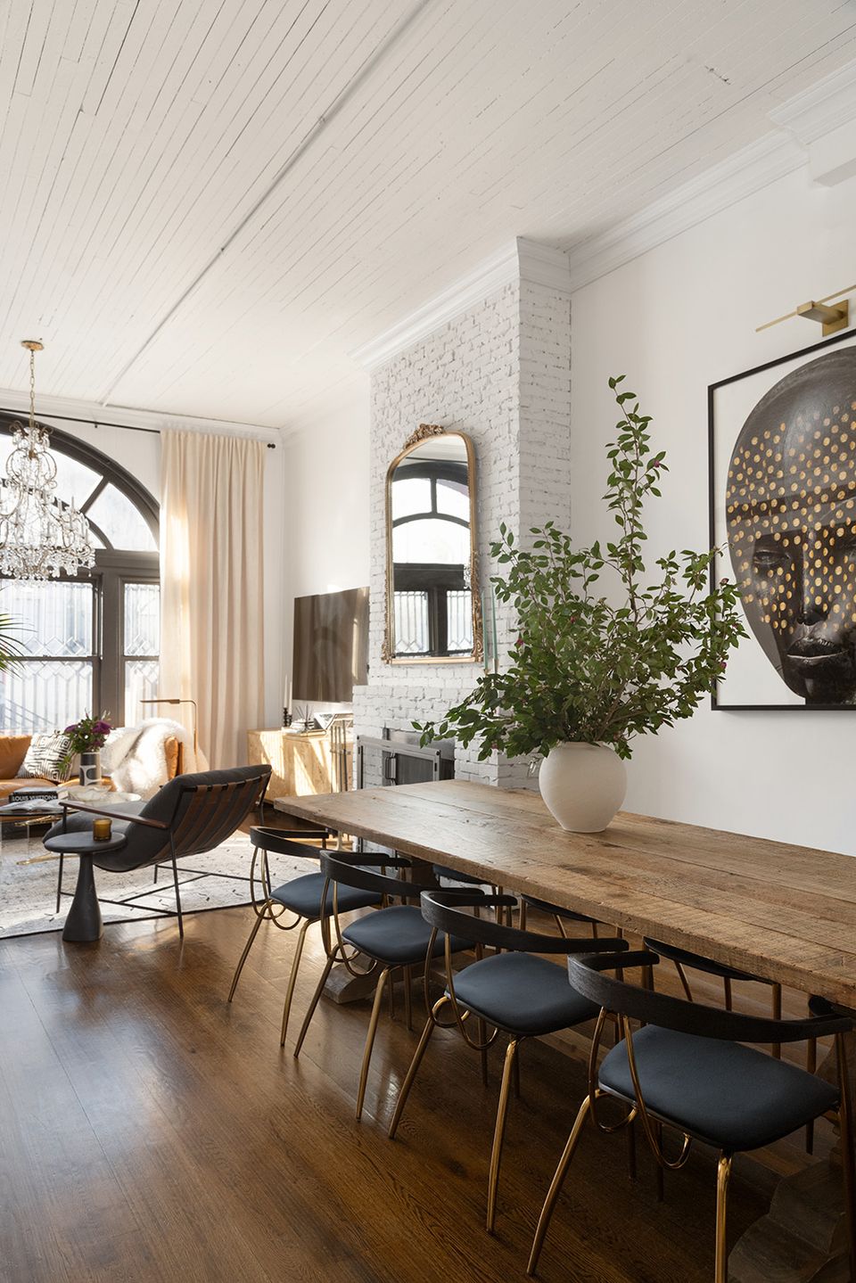 Scandinavian dining space with white brick, natural wood table, and potted greenery creating airy minimalist elegance.