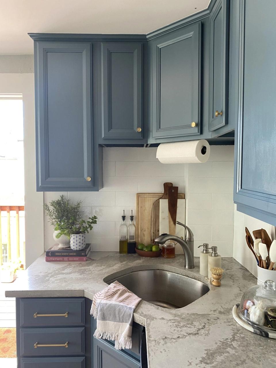 Cottage kitchen with slate-blue painted cabinets, white subway tile backsplash, and marble countertops creating a classic farmhouse aesthetic.