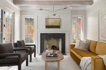 Balanced living room with fireplace, ochre and charcoal seating, natural wood accents, and bright windows in contemporary-traditional style