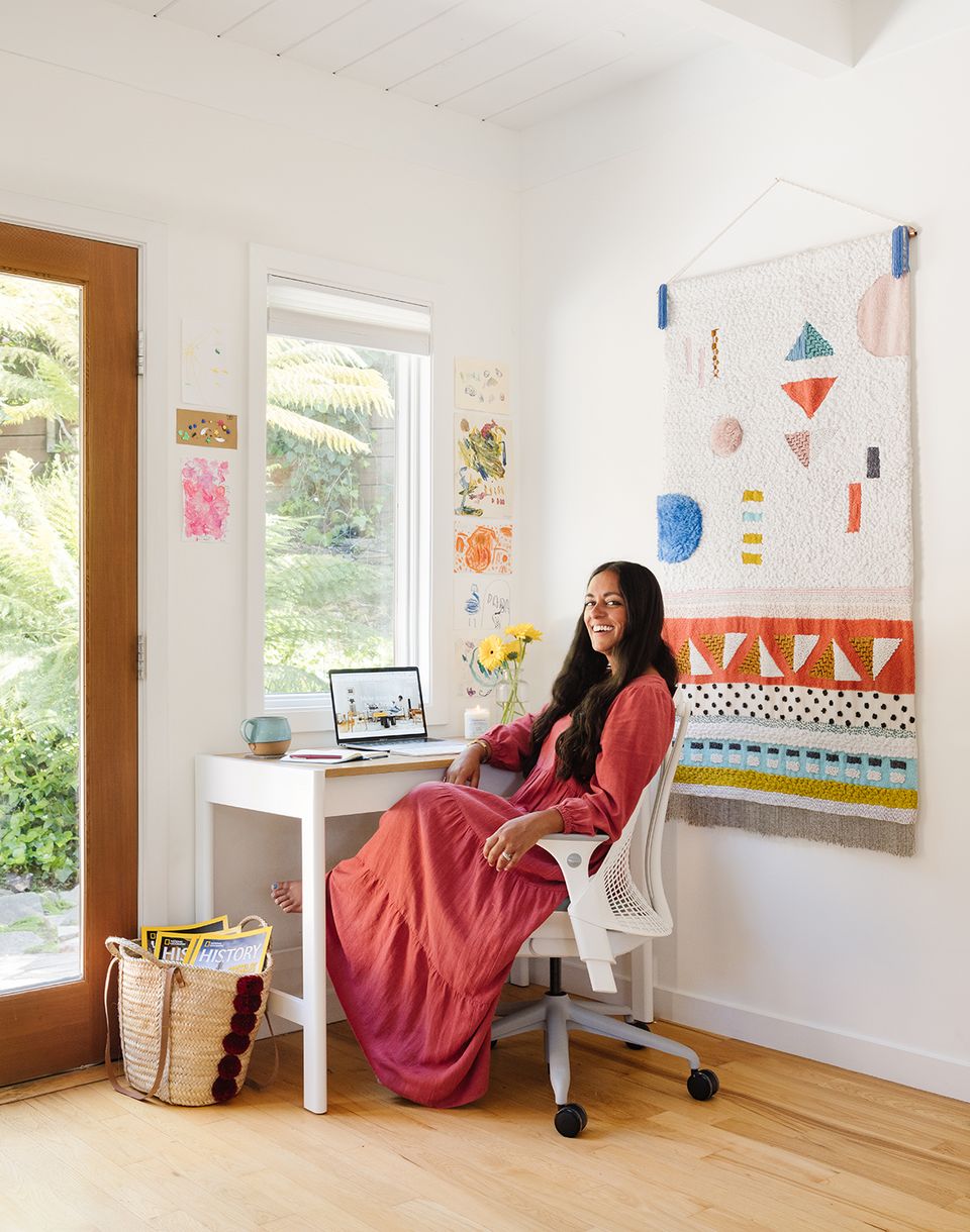Bright boho workspace with colorful geometric wall art, coral accent chair, and natural wood door
