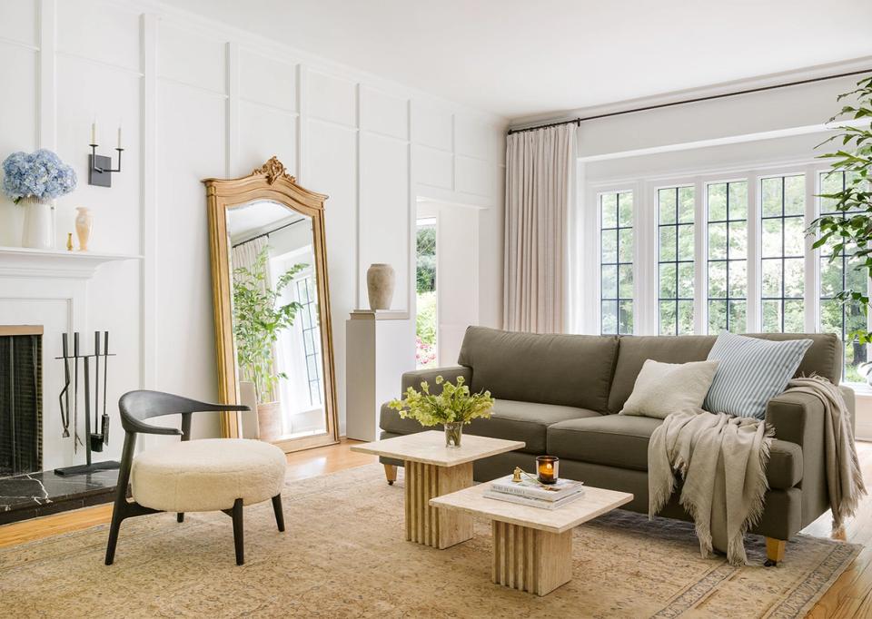 Transitional living room with olive-green sofa, warm wood accents, and natural light from French doors