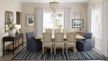 Classic coastal dining room with cream walls, navy accent chairs, striped rug, and chandelier lighting