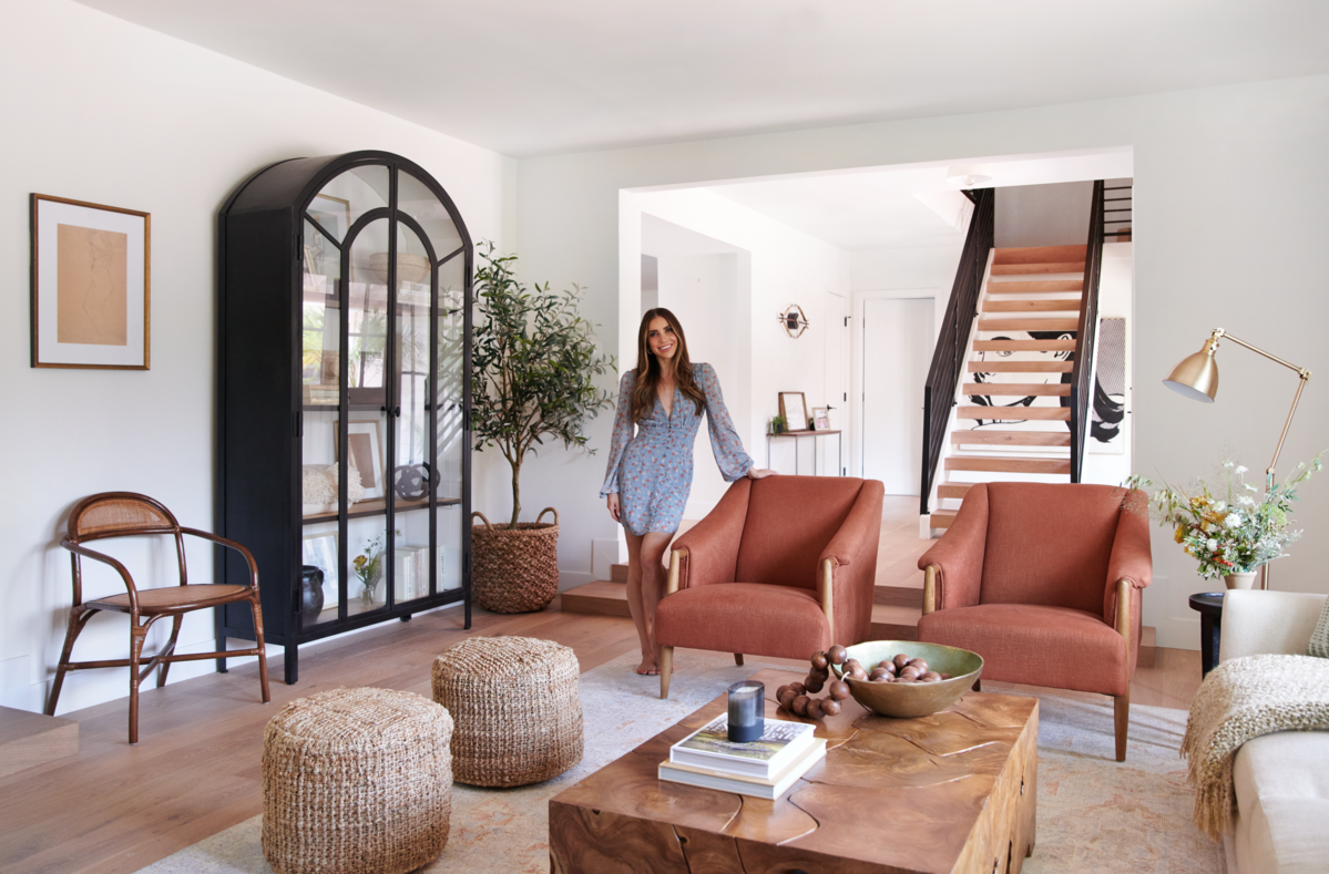 Bright California-cool living room with terracotta sofas, natural wood accents, and arched black doorway against white walls.