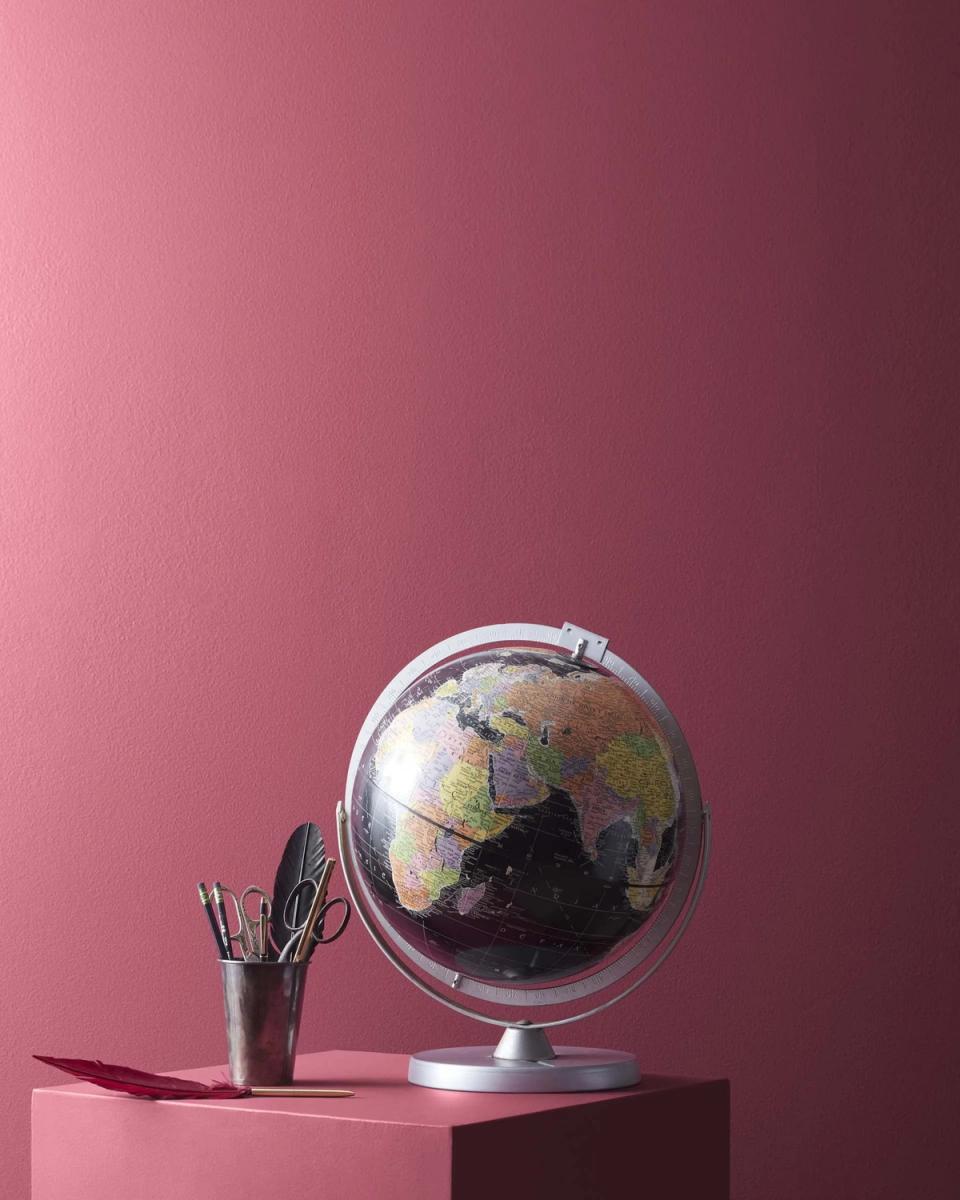 Contemporary rose-pink minimalist space with metallic globe and desk accessories on geometric platform