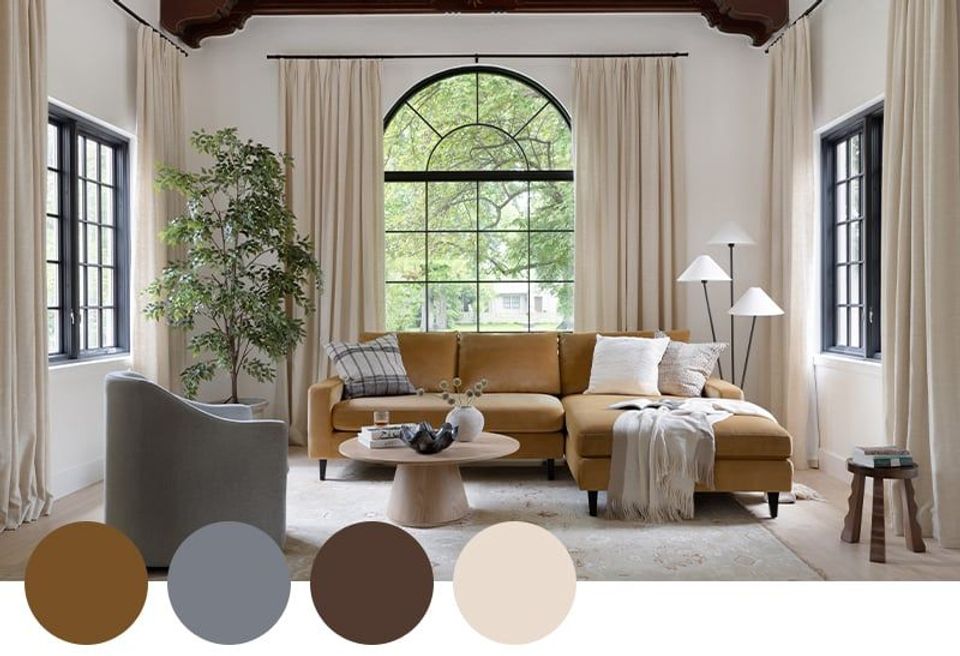 Warm transitional living room blending mustard, slate blue, and cream with arched window and exposed beam ceiling.