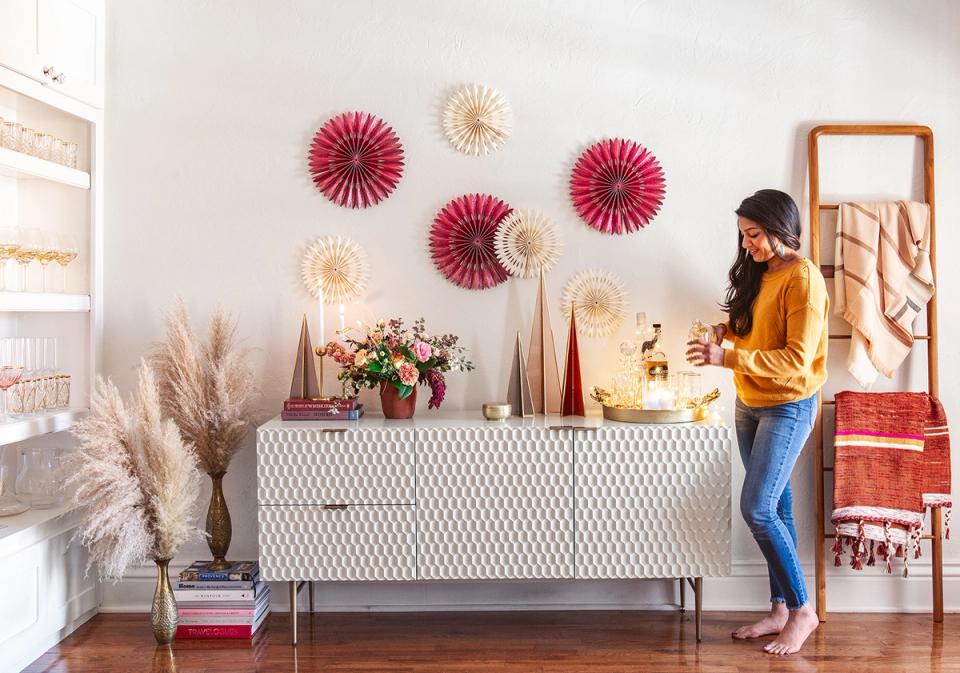 Modern console styling with colorful paper fans, pampas grass, and jewel-toned holiday accents on white walls