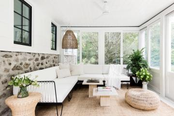 Bright sunroom with coastal minimalist design, cream seating, natural textures, and abundant greenery