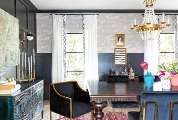 Modern eclectic home office with dark charcoal walls, gold accents, brass chandelier, and bold patterned wallpaper creating vibrant, artistic workspace