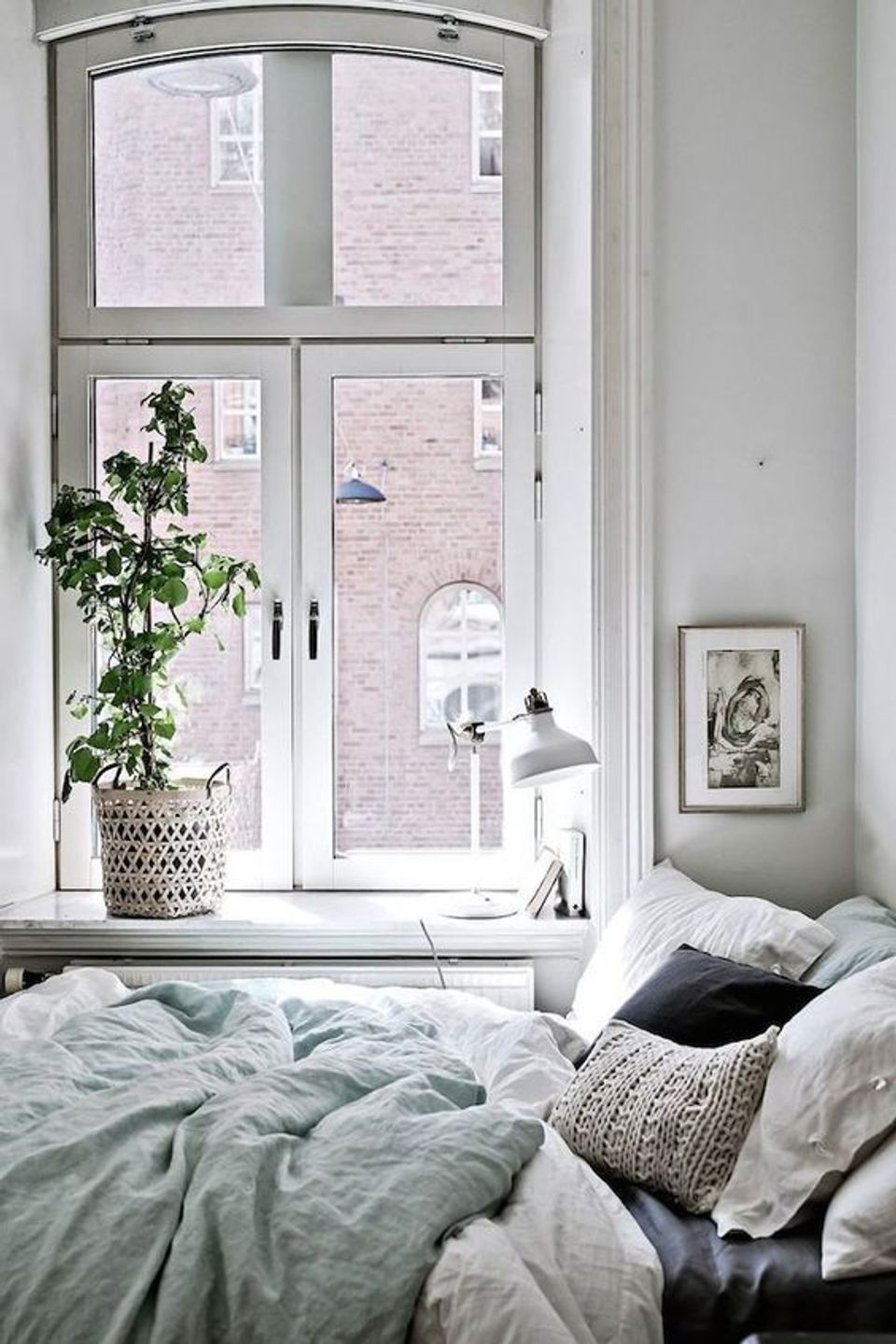 Serene bedroom window seat with soft linen bedding, woven plant pot, and neutral aesthetic