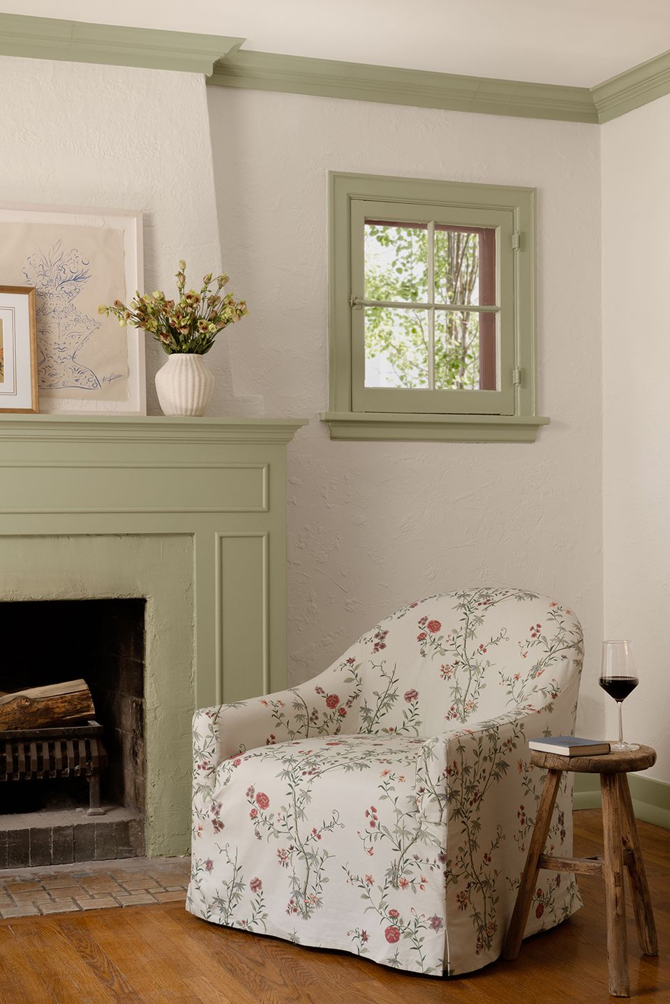 Sage green fireplace mantel with floral chair and vintage botanical details