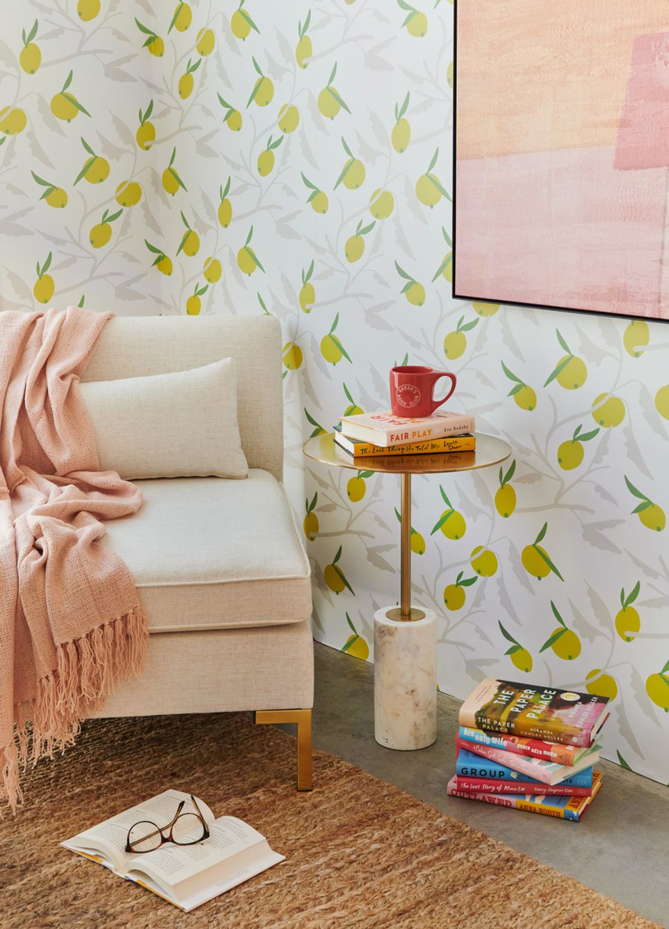 Serene reading corner with cheerful lemon-print walls, cream armchair, warm wood side table, and soft pink accents