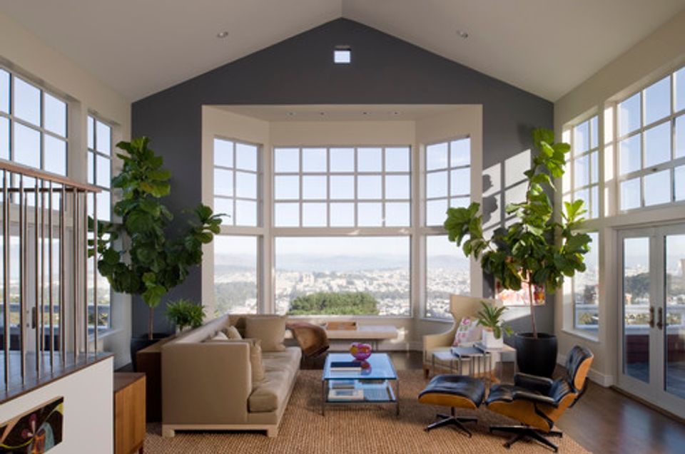 Modern living room with floor-to-ceiling windows, dark accent wall, and minimalist mid-century furniture