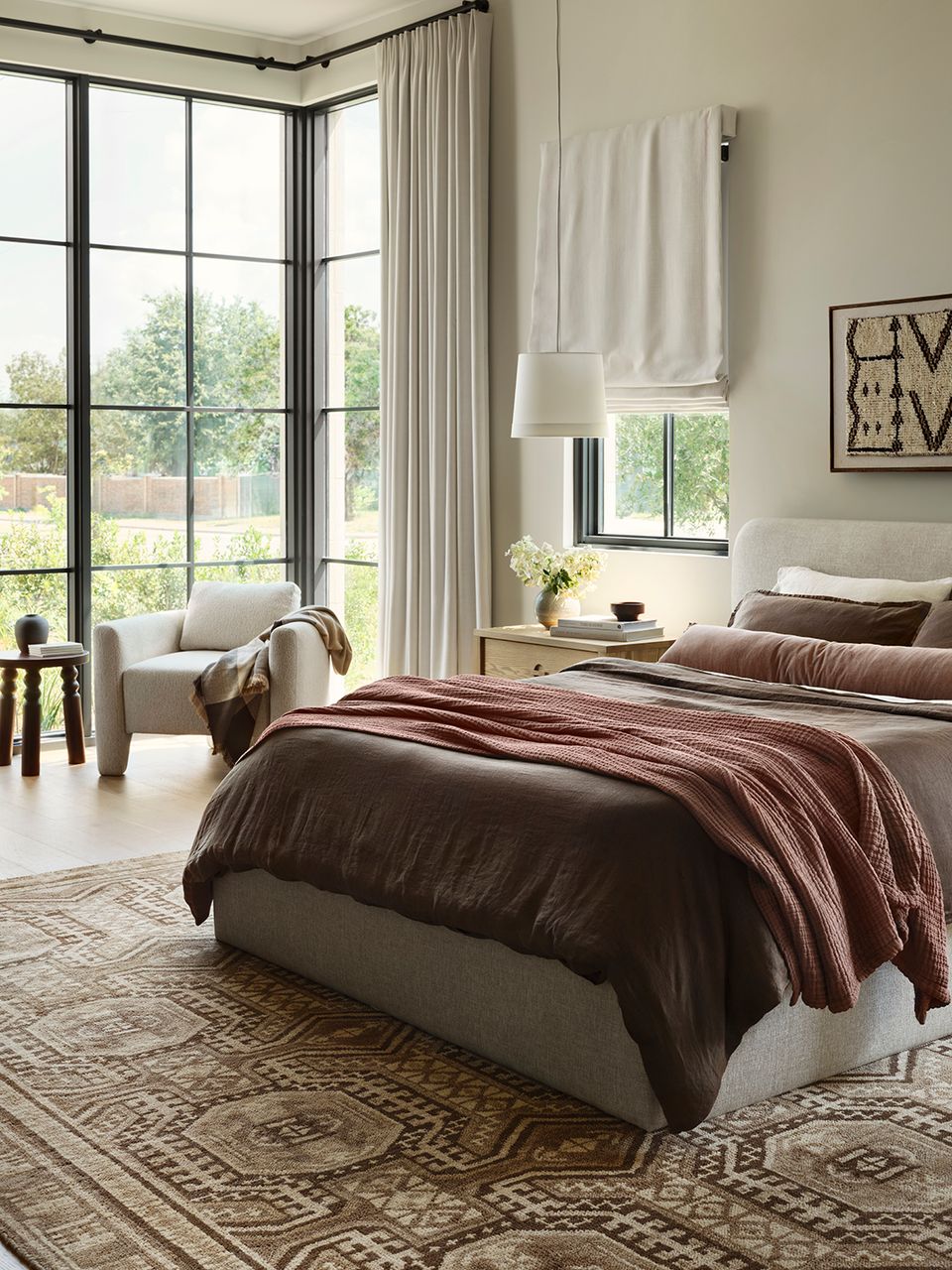 Spacious boho bedroom with burgundy bedding, geometric rug, and floor-to-ceiling windows
