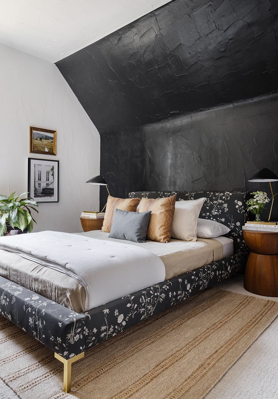 Modern bedroom featuring dramatic black accent wall, botanical bedding, and warm wood details
