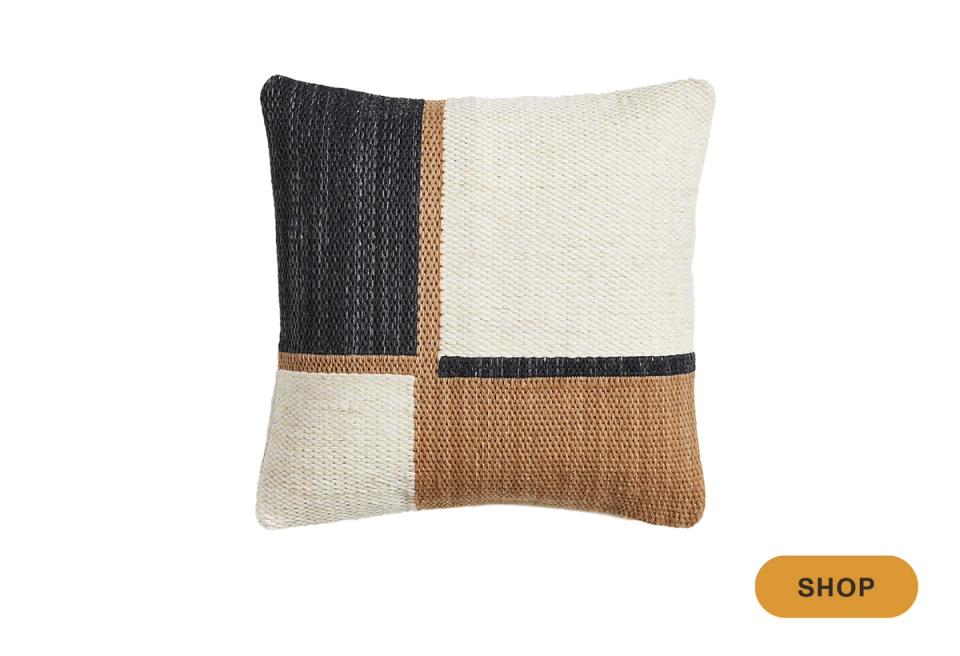 Color-block pillow combining cream, charcoal, and tan textures in modern composition