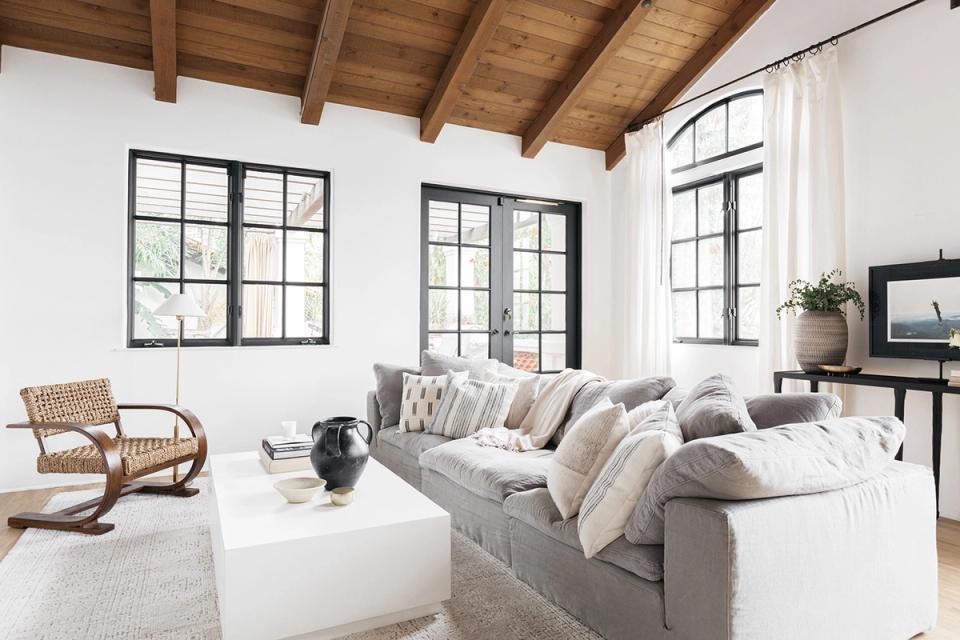 Scandinavian-inspired living room with exposed wooden beams, gray sectional, natural fibers, and minimalist styling