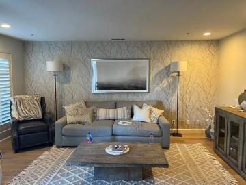 Sophisticated neutral living room with textured wallpaper, blue-gray sofa, and warm ambient lighting creating an elegant, welcoming atmosphere