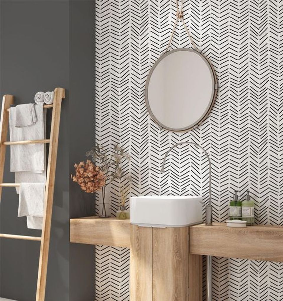 Modern bathroom with geometric chevron wallpaper, natural wood vanity, and warm neutral palette