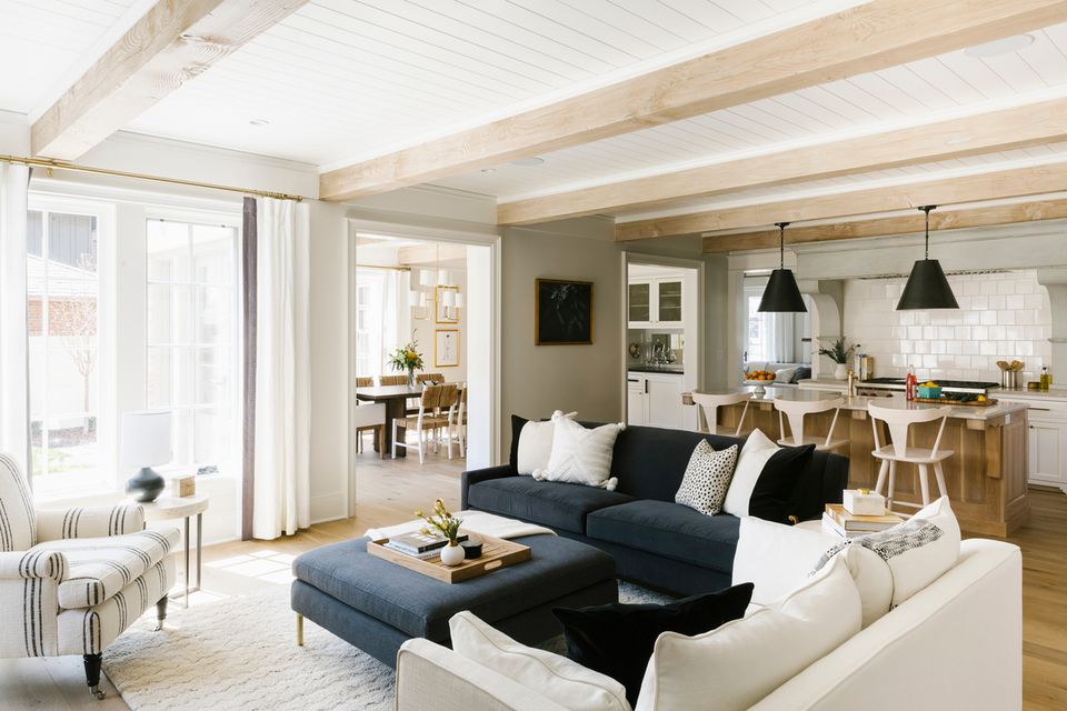 Bright modern farmhouse living room with navy sofa, white accents, natural wood beams, and pendant lighting