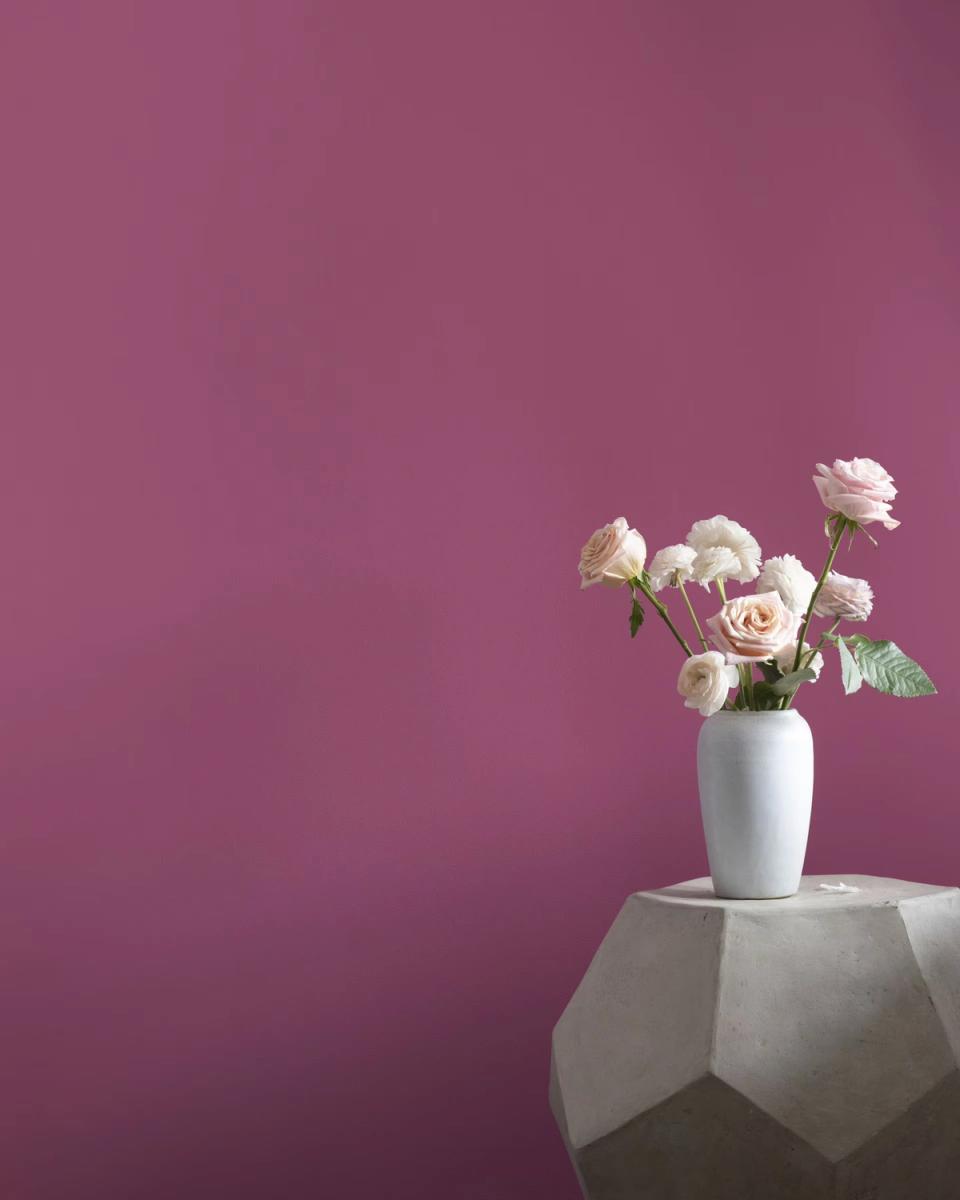 Elegant mauve-pink modern space featuring white ceramic vase with fresh roses on geometric table