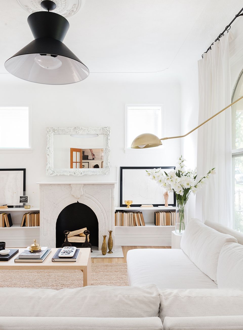 Modern minimalist living room with black fireplace, white built-ins, industrial pendant light, and clean Scandinavian-inspired aesthetic