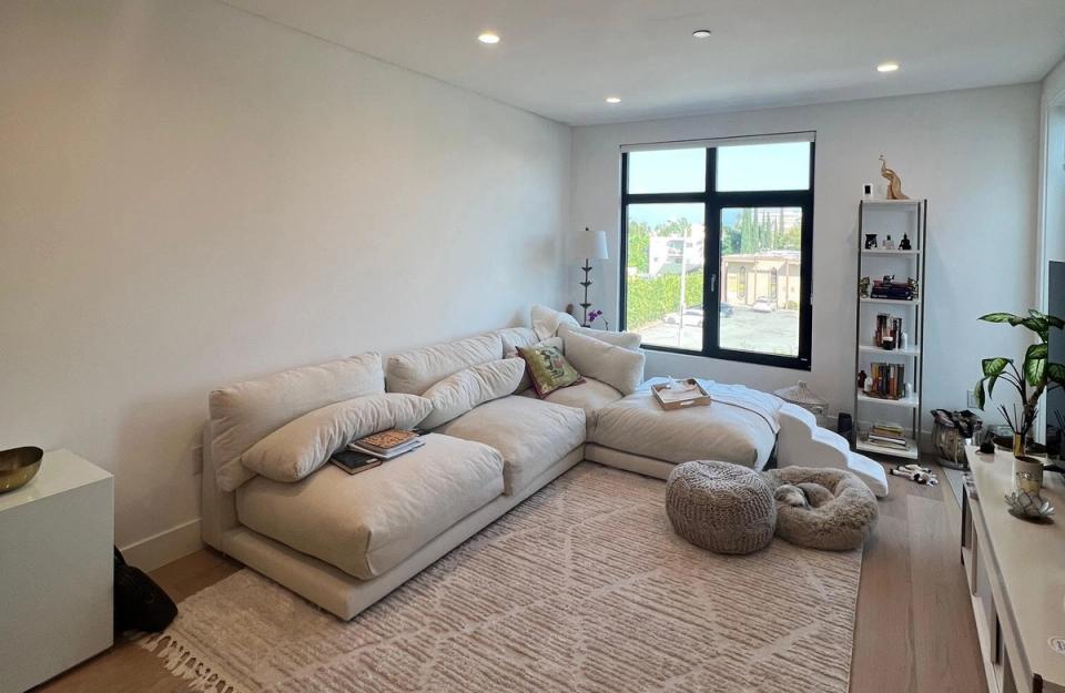 Serene, neutral media room featuring a sectional sofa with layered cushions and soft, calming earth-tone palette throughout.