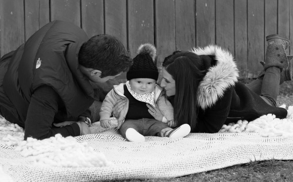 Cozy monochromatic scene of three people bundled in winter coats on a textured blanket, conveying warmth and intimate comfort