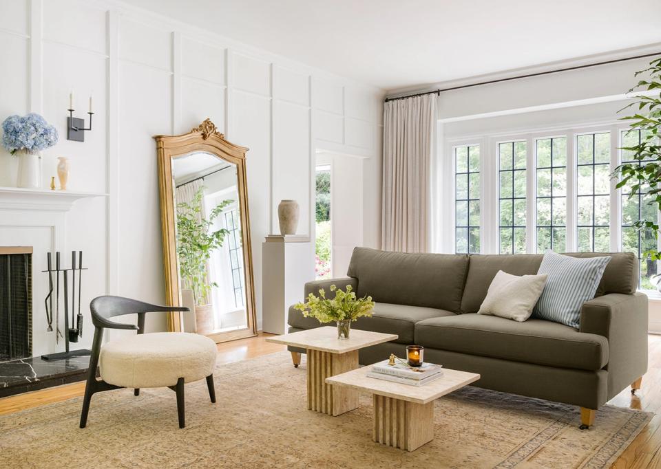 Contemporary living room with sage green sofa, mid-century furniture, and minimalist white shiplap walls