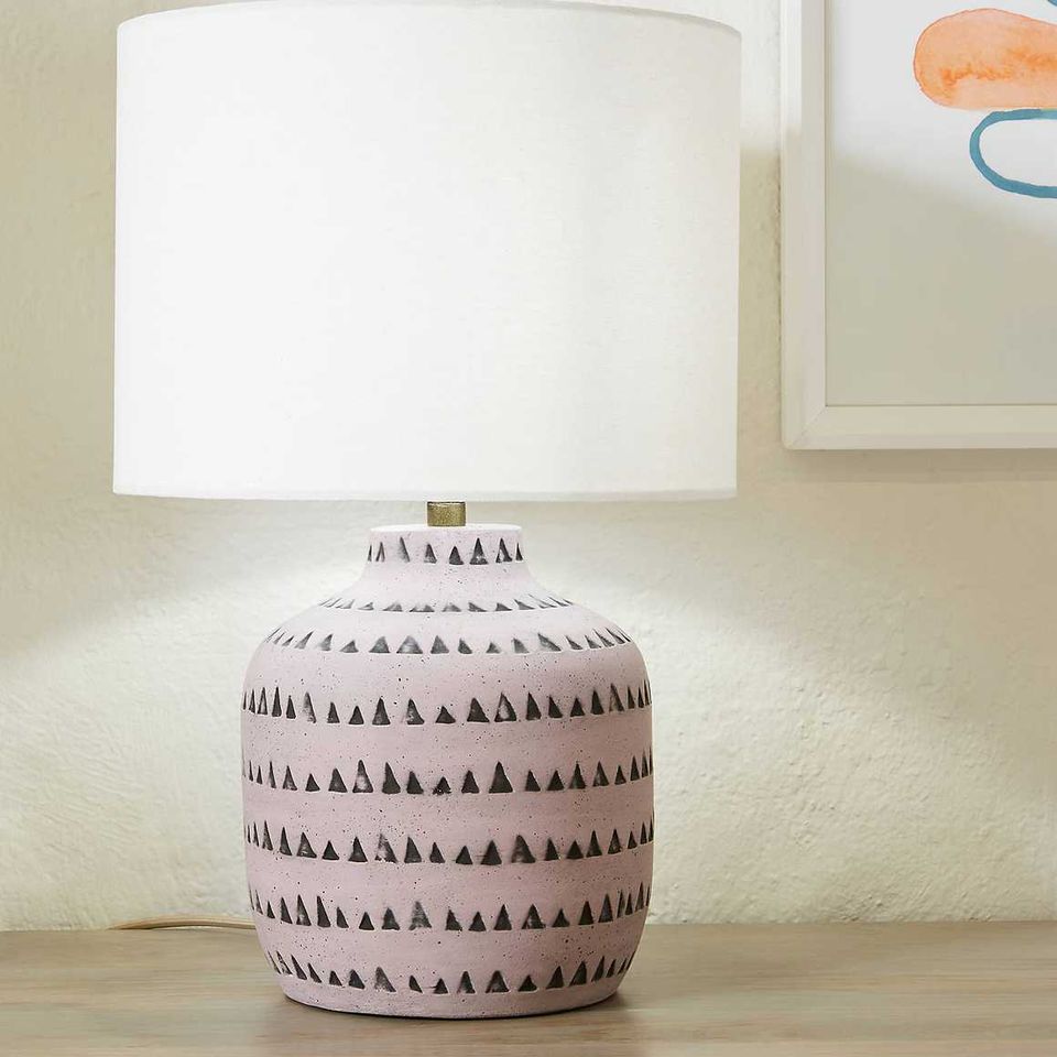 Modern geometric table lamp with patterned ceramic base and white drum shade on neutral backdrop