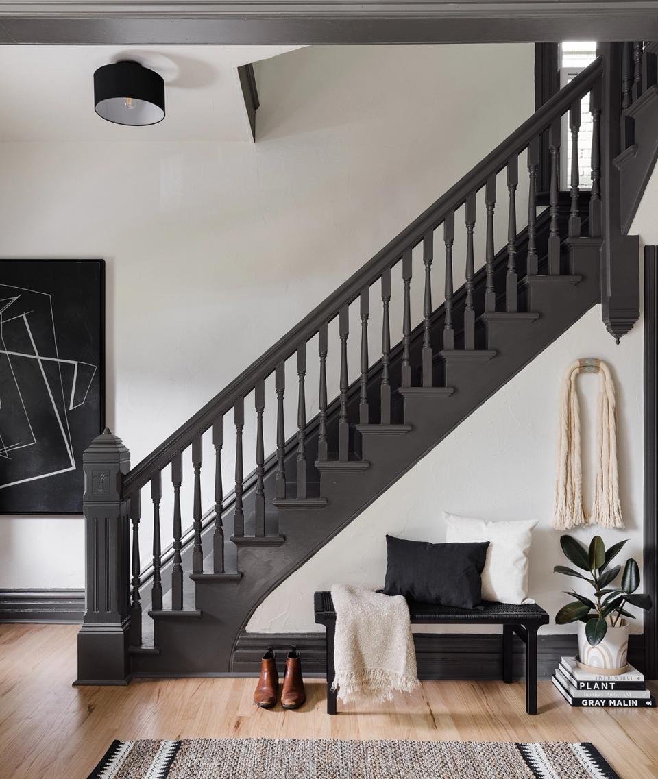 Contemporary entryway with dramatic black staircase, white walls, and minimalist black bench seating