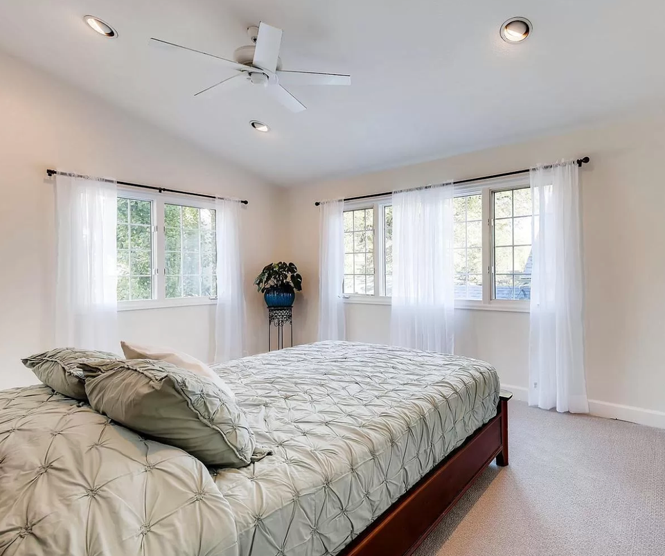 Bright minimalist bedroom with sheer white curtains, neutral bedding, and abundant natural light