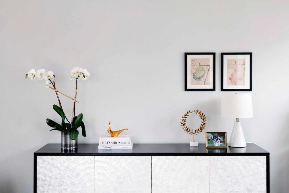 Minimalist Scandinavian console with white marble and black frame, neutral palette with botanical accent