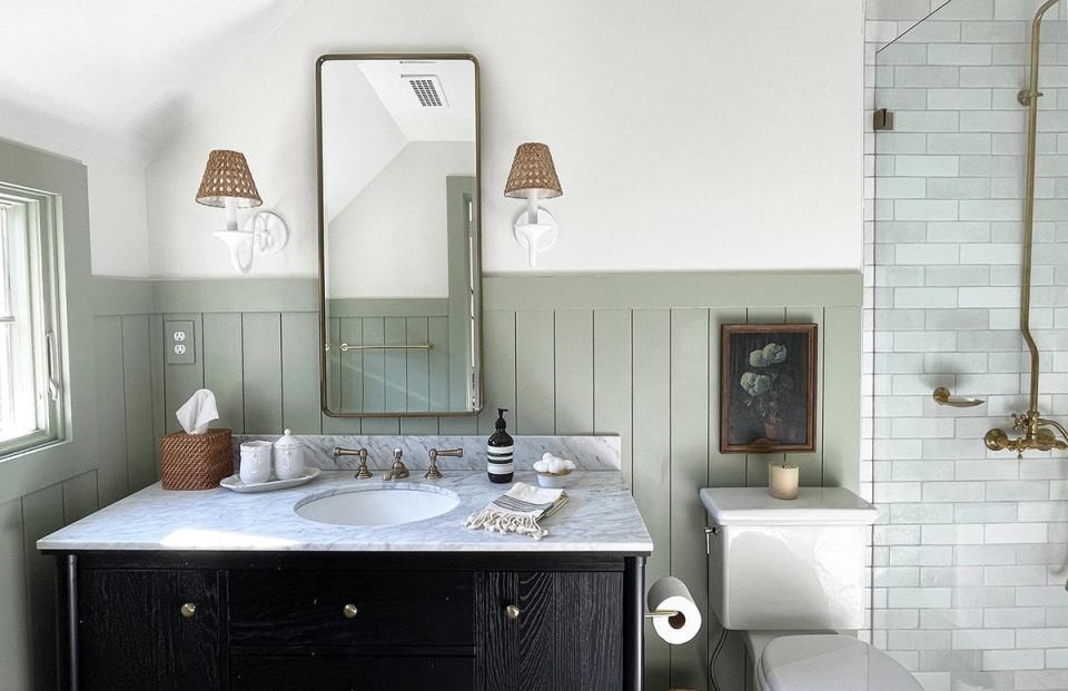 Spa-like bathroom with sage green shiplap wainscoting, black vanity, and classic subway tile