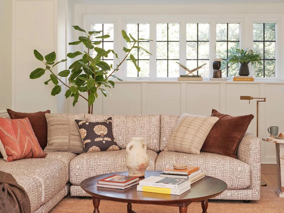 Eclectic cottage corner with patterned upholstery, layered textiles in coral and burgundy, and abundant natural light