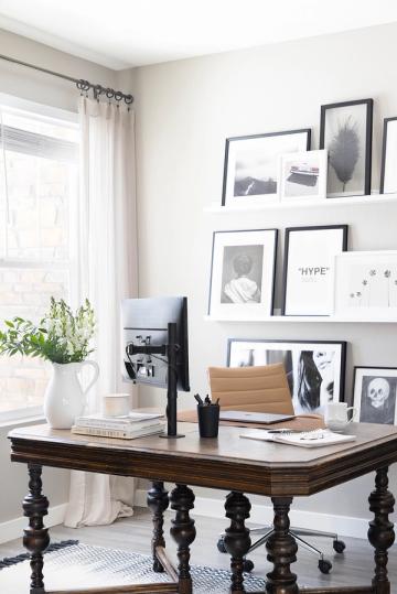 Modern office with floating shelves, symmetrical black-framed prints, white palette, desk, and minimalist monochrome aesthetic.