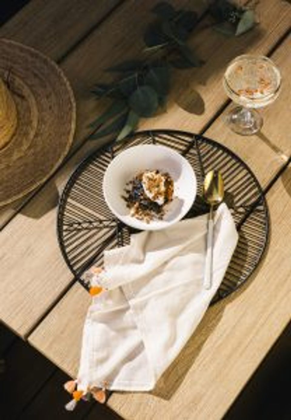 Organic modern outdoor place setting with natural textures, white napkin, and eucalyptus accents