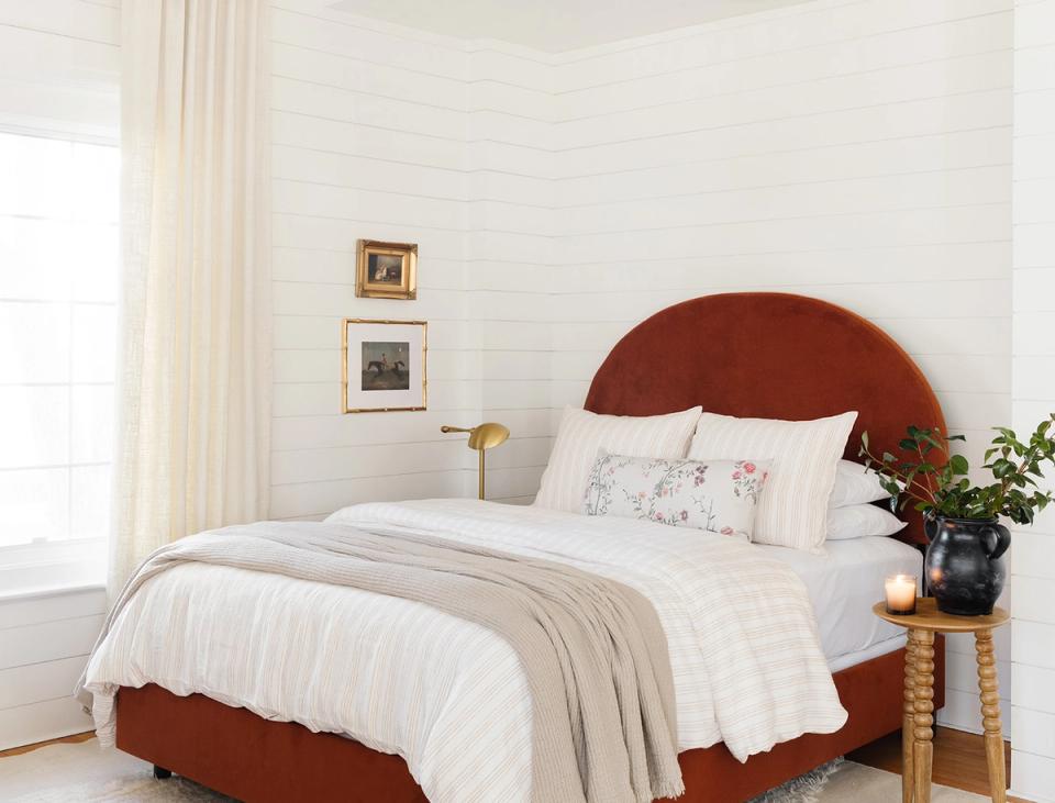 Contemporary bedroom with terracotta velvet headboard, cream linens, white walls, and minimalist styling