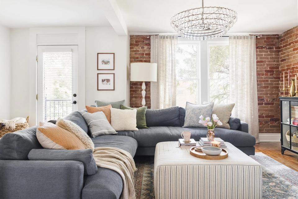 Warm contemporary living room with charcoal sectional, exposed brick, and neutral accents