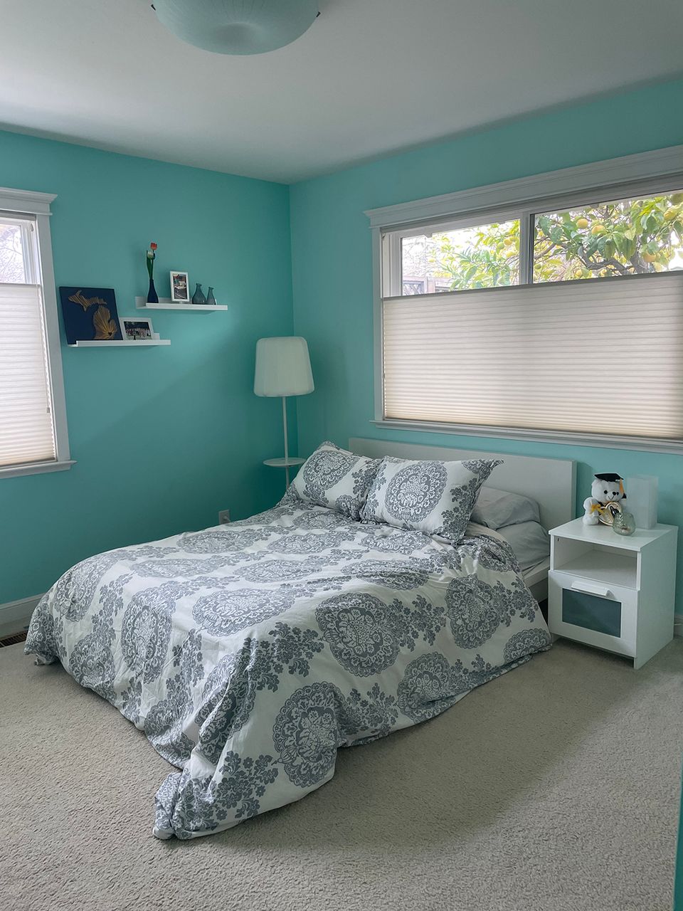 Dated turquoise bedroom with bright walls, simple furnishings, and patterned bedding—cluttered 2000s style