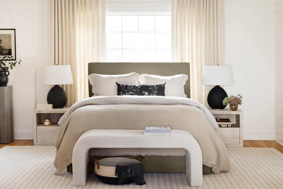 Modern bedroom with sage green headboard, neutral bedding, and bench storage at foot of bed