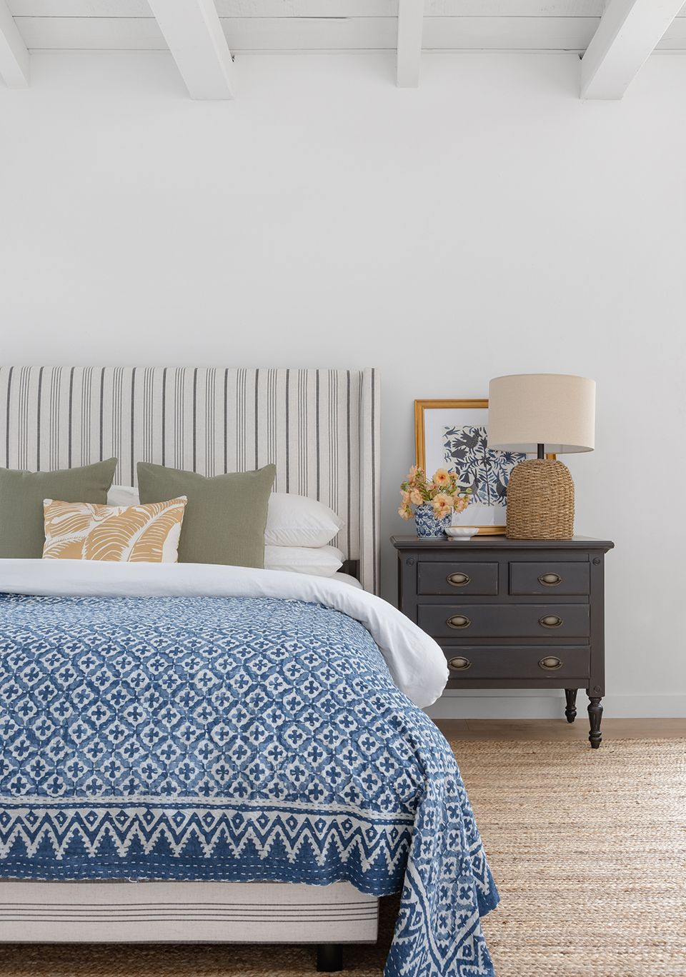 Coastal-inspired bedroom with blue geometric bedding, white shiplap headboard, and natural wood accents
