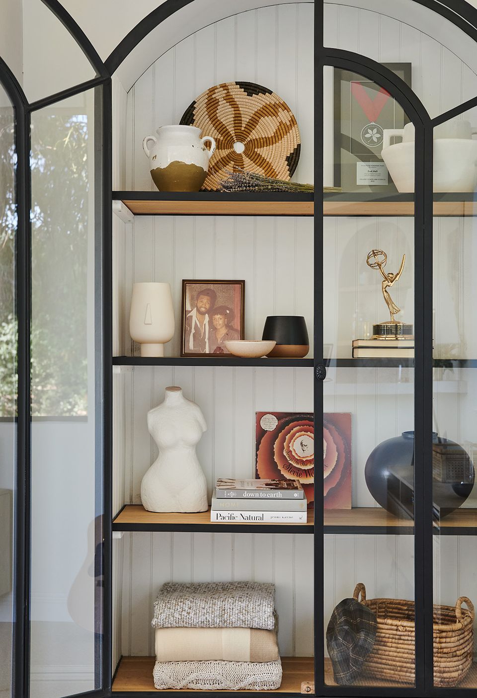 Eclectic black-framed display cabinet with warm wood shelves and curated accessories