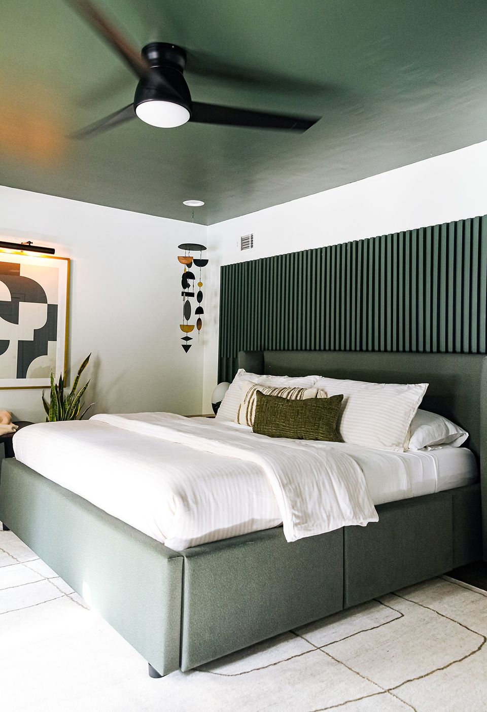 Modern bedroom with sage green vertical slat accent wall, soft white bedding, and sage ceiling