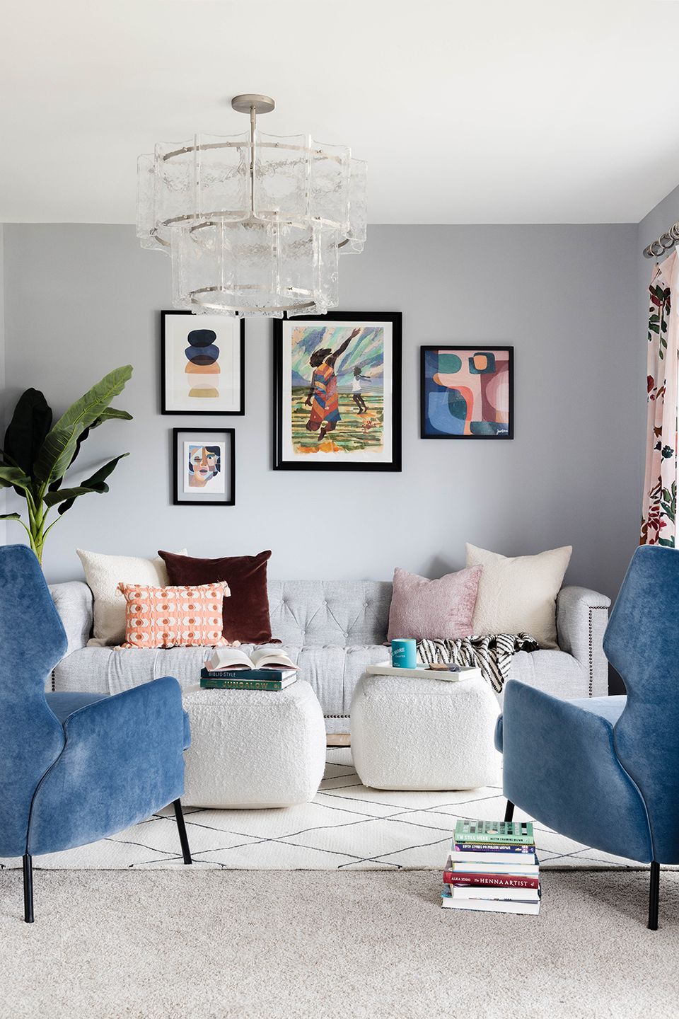 Balanced dual-seating reading room with navy chairs, gallery wall, and soft multicolored accent pillows