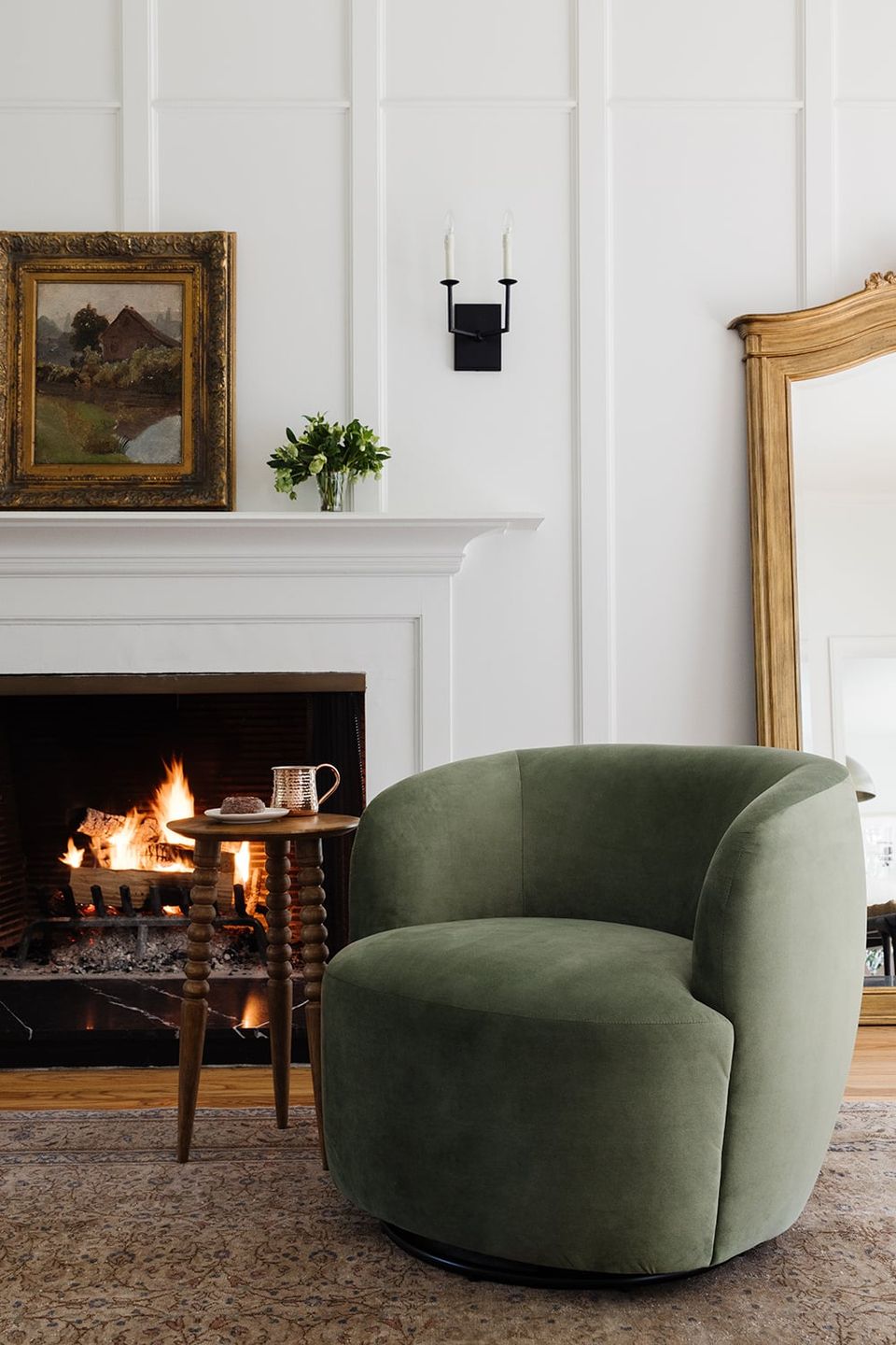 Contemporary sage green swivel chair by fireplace in classic British interiors setting