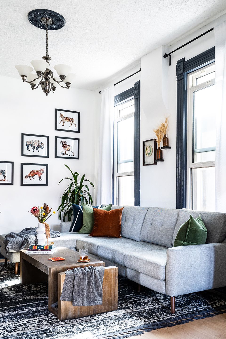 Eclectic modern space with gallery wall art, gray sofa, and vintage-inspired wood coffee table