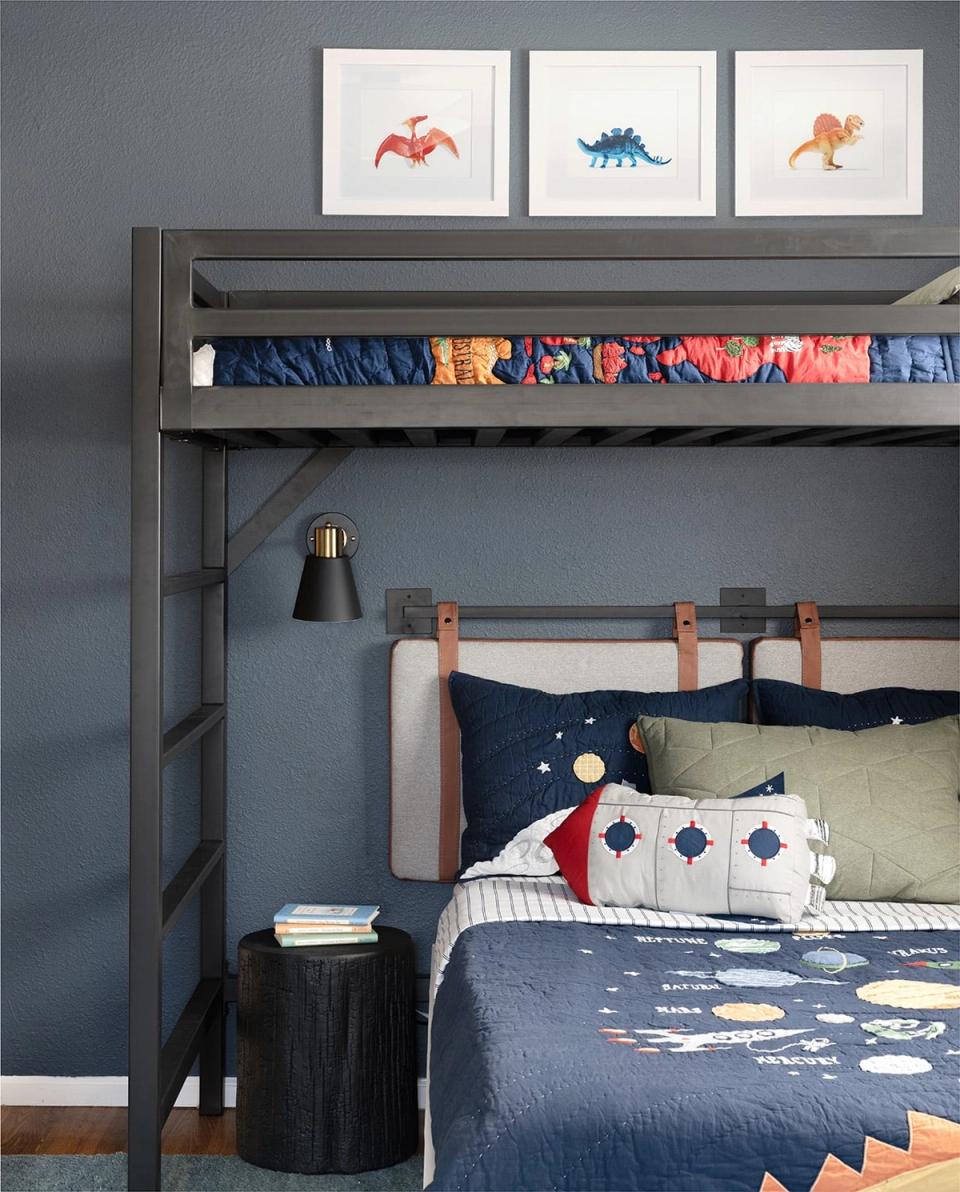 Modern loft bedroom in slate blue with colorful dinosaur artwork, navy bedding, and brass accents balancing playfulness with contemporary design